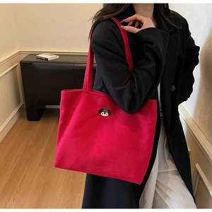 Detail of red canvas tote bag featuring dog embroidery styled with a black coat