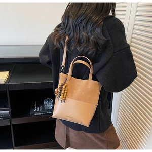 Détail du sac seau marron clair avec breloque en perles de bois et cuir en patchwork