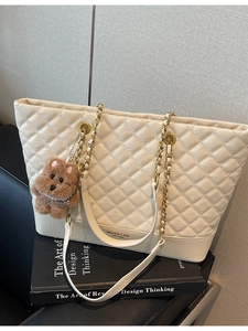 Sac cabas beige matelassé avec bandoulière chaîne dorée et breloque ours élégante