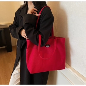 Detailed close-up of a red canvas tote bag featuring a cute cartoon dog embroidery