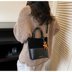 Détail du sac seau noir avec finition mate et pendentif en perles de bois