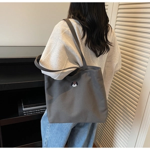 Detail of dark grey canvas tote bag featuring dog embroidery and large shoulder straps
