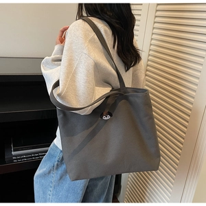 Detail of dark grey canvas tote bag with cartoon dog badge shown on a shoulder