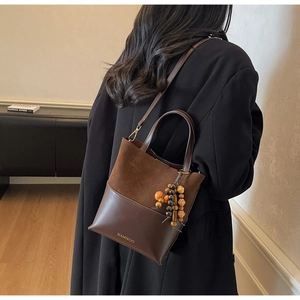 Detail of vintage brown tote bag with suede and leather patchwork and wooden bead charm
