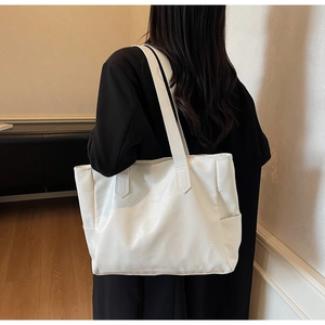 Close-up of white leather tote bag texture with subtle embossed minimalist lettering