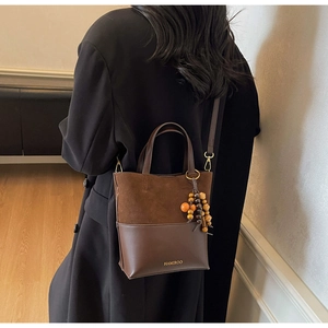 Détail d'un sac cabas marron mat avec lettrage doré et glands décoratifs en perles