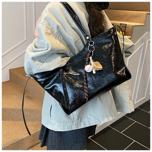 Détail du sac cabas en cuir verni plissé noir avec accessoire de charme de baseball