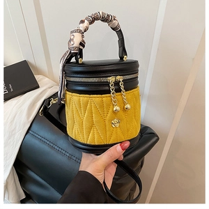 Detailansicht der gesteppten Zylindertasche aus schwarzem Leder und gelbem Wildleder