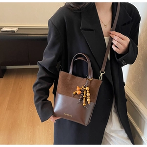Détail du sac seau en daim mat et cuir lisse avec breloque en perles rétro