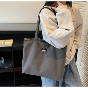 Detailed view of dark grey canvas tote bag featuring embroidered puppy dog portrait