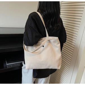 Close-up of beige canvas tote bag featuring cute dog embroidery worn by a model