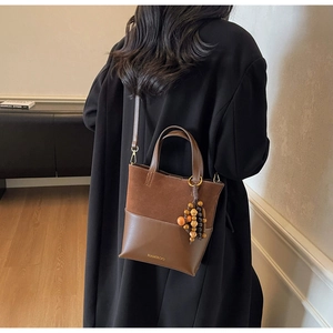 Détail du sac seau vintage en daim marron avec breloque décorative en perles