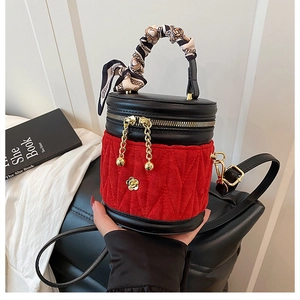Detail einer Beuteltasche aus rotem Samt und schwarzem Leder mit Goldrose und Seidenschal-Griff