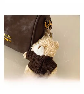 Gros plan d'un charmant ours en peluche tricoté attaché à un sac polochon marron chic