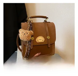 Details des braunen Vintage-Rucksacks mit Cartoon-Stickerei und Teddybär-Anhänger-Zubehör
