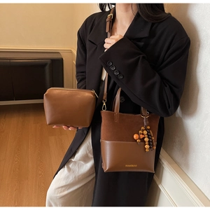 Gros plan sur un sac cabas marron mat avec breloque perlée et pochette assortie
