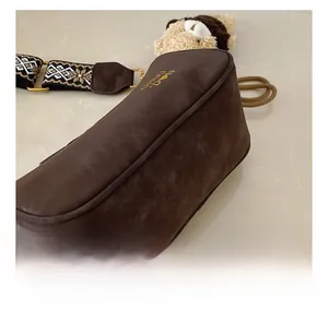 Détail du sac polochon en daim marron mat avec bandoulière large à motifs ethniques