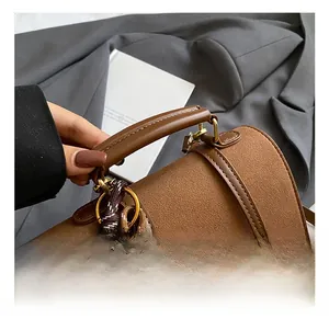 Detail der braunen Ledertasche mit Bärenstickerei und einem geflochtenen Anhänger