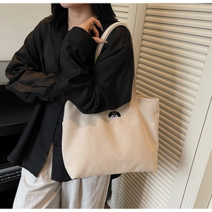 Close-up of minimalist cream canvas tote bag with a small embroidered bulldog puppy detail