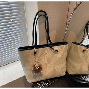 Detailed texture of green marble-patterned tote bag with plush monster charm and black strap