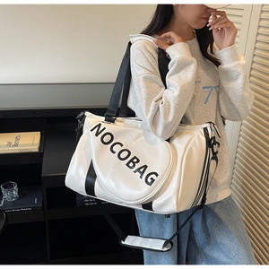Weiße Oversize-Reisetasche aus PU-Leder mit großem schwarzem Schriftzug im Lifestyle-Ambiente