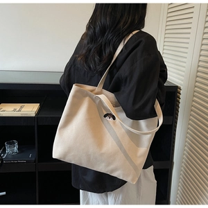 Detailed embroidery of a puppy on a minimalist beige canvas tote bag worn by a model