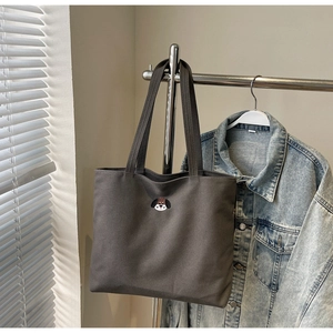 Detail of dark canvas tote bag featuring a cute dog embroidery and long shoulder straps