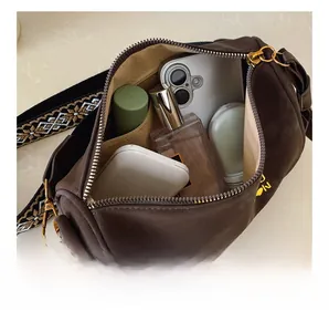 Vue de dessus d'un sac cylindrique marron vintage avec espace pour téléphone et parfum