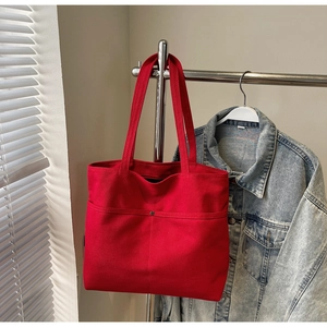 Detail of red canvas tote bag with large front pocket and metal rivet reinforcement