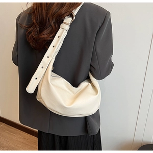 Detail der cremefarbenen Hobo-Tasche mit silbernen Metallösen am breiten Schultergurt