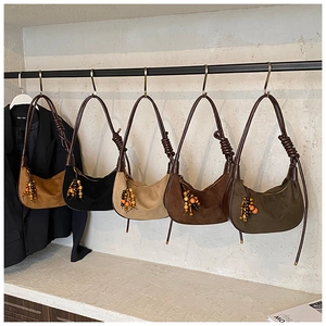 Detail of five suede hobo bags with knotted straps and colorful beaded tassel charms