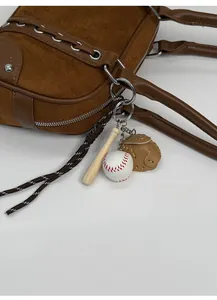 Detail of three-in-one baseball, bat and glove charm attached to a brown suede bag