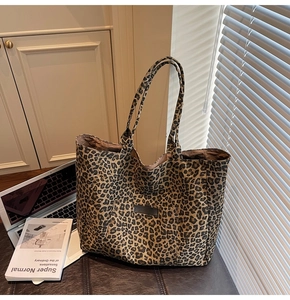 Leopard print canvas tote bag with large capacity and double straps on a leather bench