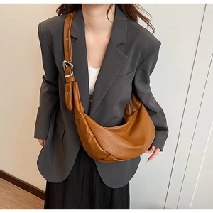 Brown oil wax leather crescent bag shown on model with wide shoulder strap and silver buckle