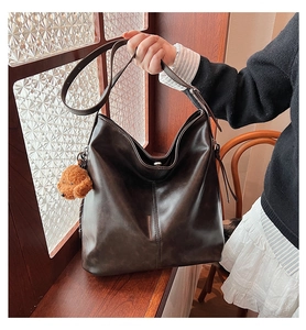 Détail du sac seau en cuir marron foncé avec un charmant pendentif ours en peluche