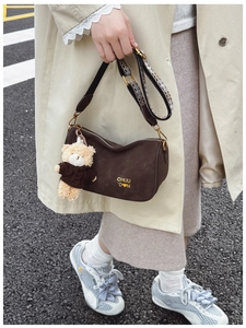 Détail du sac polochon marron foncé avec bandoulière géométrique et petit ours