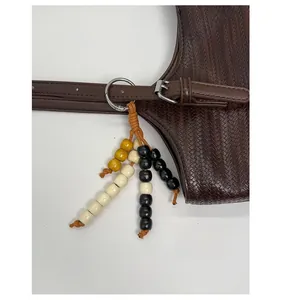 Gros plan d'un pendentif en perles fait main sur un sac vintage avec anneau métal