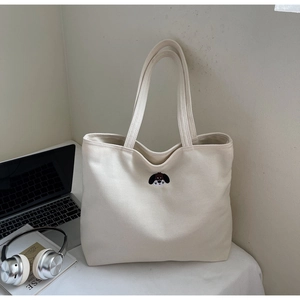 Detailed embroidery of a cartoon dog head on an off-white canvas tote bag