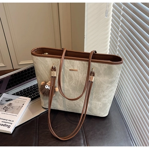 Detail of grey marble texture tote bag with brown trim and plush charm in office setting