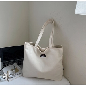 Detailed view of the ivory canvas tote bag with a cute colorful dog embroidery