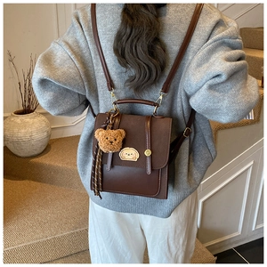 Detailansicht eines braunen Kunstlederrucksacks mit Bärenanhänger an einem Model