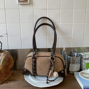 Detail of vintage brown suede Boston bag with side metal eyelets and a baseball charm
