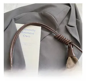 Detailed view of the dark brown matte suede shoulder bag with unique knotted strap detail