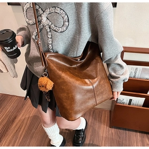 Sac seau vintage en cuir marron avec surpiqûres verticales et charmant pendentif ours