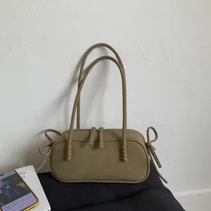 Détail du sac sous l'aisselle vert mat avec des nœuds décoratifs et double fermeture