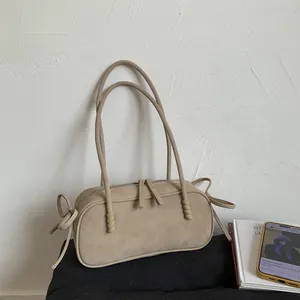 Détail du sac à bandoulière en daim beige mat avec double fermeture éclair et nœuds