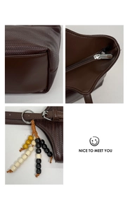 Détail du sac cabas tressé marron foncé avec fermeture éclair et charm en perles