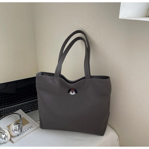 Detail of dark grey canvas tote bag with a cute dog head embroidery and long handles