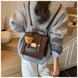 Detail eines braunen Vintage-Lederrucksacks mit Hunde-Patches und Plüschbär-Anhänger