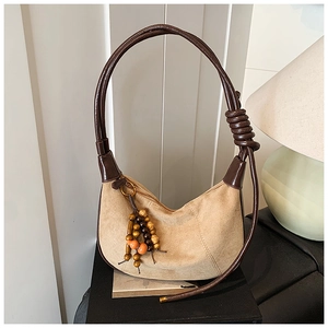 Detail of hobo shoulder bag with round knotted leather handle and bohemian beaded tassel